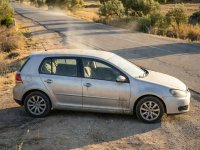 Realistic photograph of summer travel dust coating the surface of a standard European vehicle under natural lighting